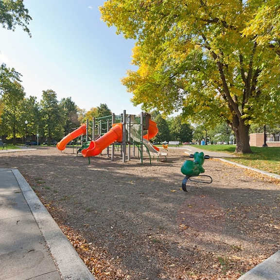 a playground with a red slide and a green ball.
