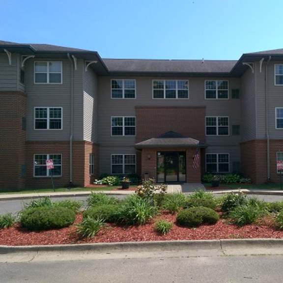 a large apartment complex with a red brick facade and a landscaped front area.