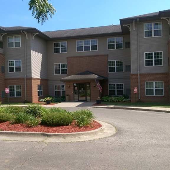 a large apartment complex with a red brick facade and a landscaped front yard.