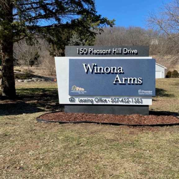 a sign for winona arms in front of a house.