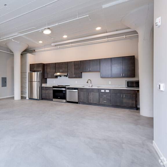 a spacious kitchen with dark cabinets and stainless steel appliances.