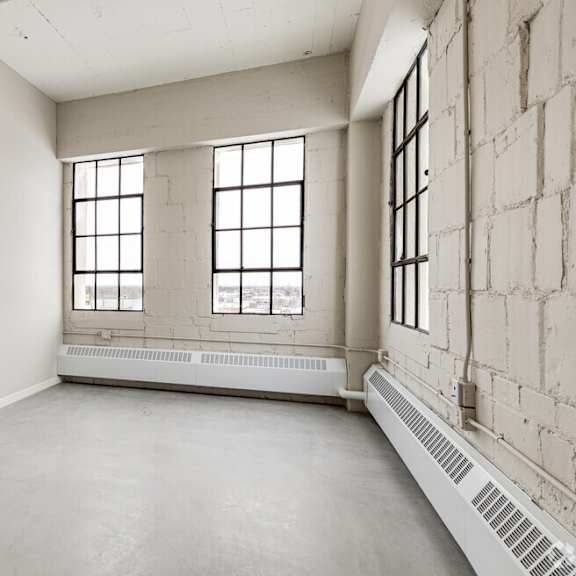 a large empty room with a window and a radiator on the floor.