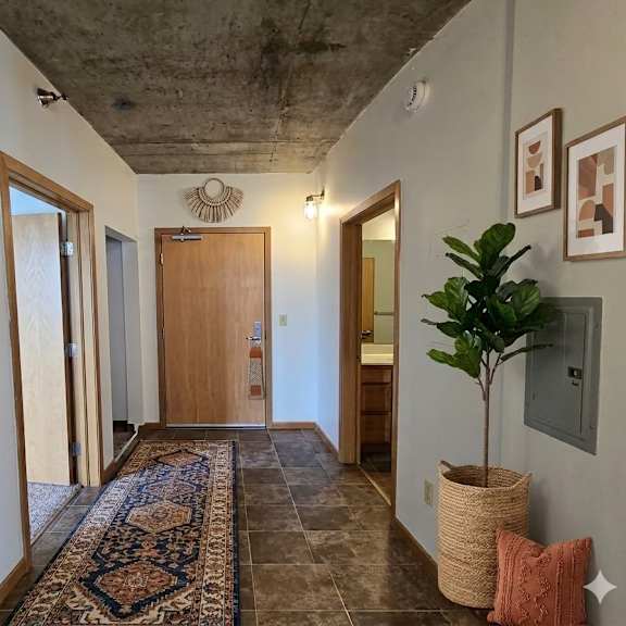 a hallway with a rug and a plant on the right side.