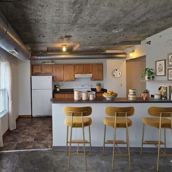 a kitchen with a white refrigerator and white cabinets with a bar area.