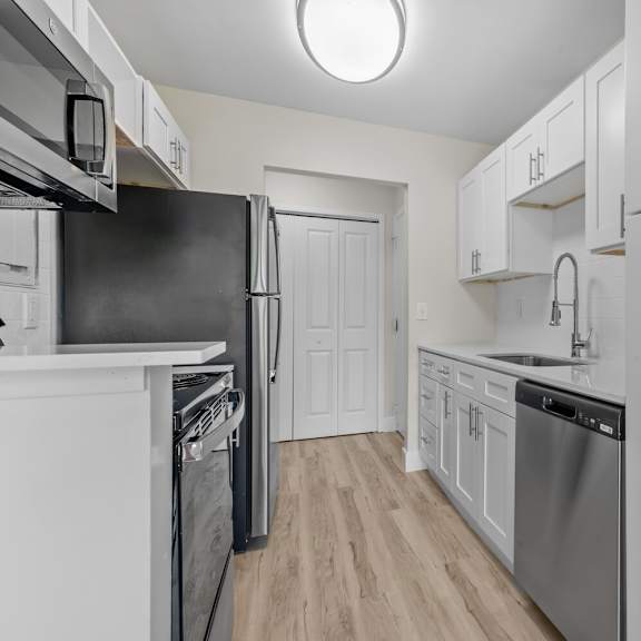 a white kitchen with stainless steel appliances and white cabinets at sunnymede apartments - troy, mi, michigan, 48084