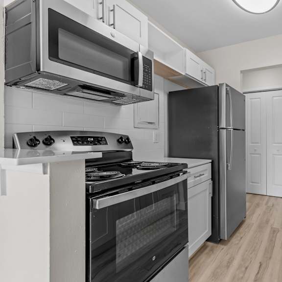 a renovated kitchen with stainless steel appliances and white cabinets at sunnymede apartments - troy, mi, troy, mi, 48084