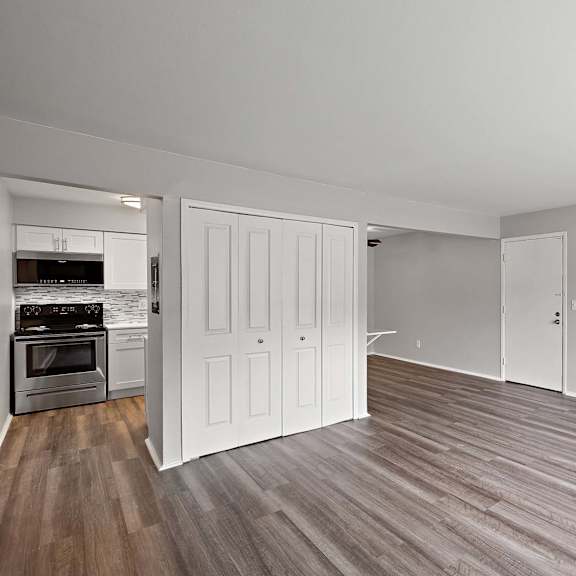 the living room and kitchen of an apartment with wood flooring