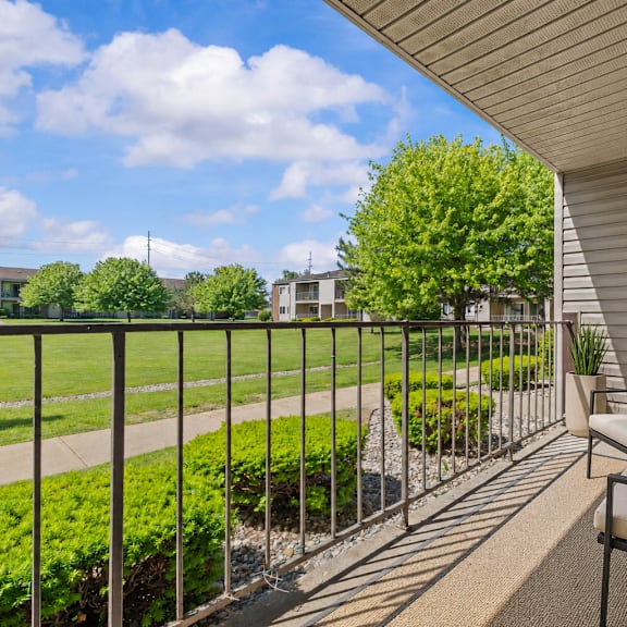 a balcony with a metal railing, a chair, and a potted plant.