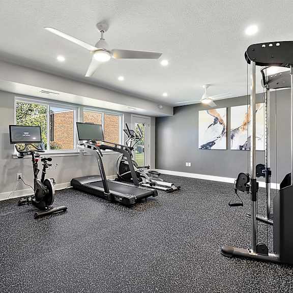 a home gym with exercise equipment and a tv at sunnymede apartments - troy, mi, troy