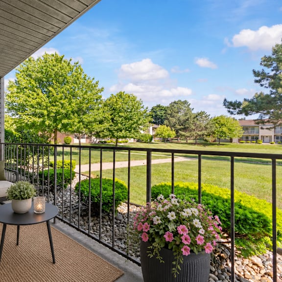 a balcony with a table, chairs, and a potted plant.