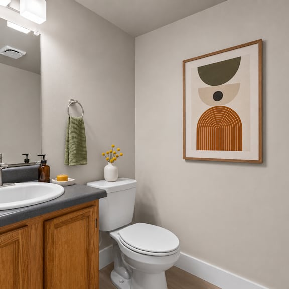 a bathroom with a toilet, sink, and a picture on the wall.
