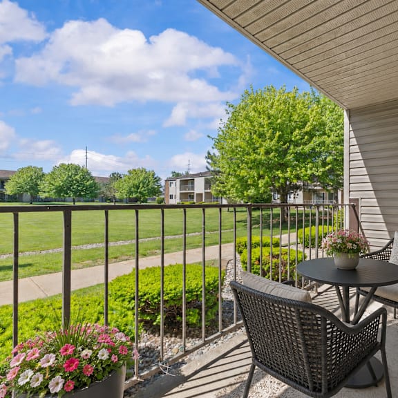 a patio with a table and chairs overlooking a green lawn.