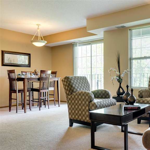 Thumbnail 6 of 7 Ridge floor plan - A living room with a brown sofa, a green armchair, and a wooden coffee table at Mallard Ridge, Maple Grove, MN