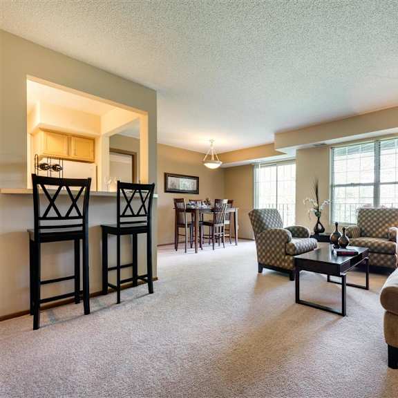 Thumbnail 7 of 7 A living room with a couch, chairs, and a dining table at Mallard Ridge, Maple Grove