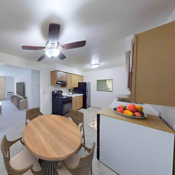 a kitchen and living room with a wooden table and a ceiling fan