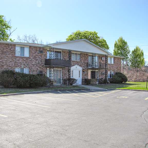 a large brick building with a parking lot in front.