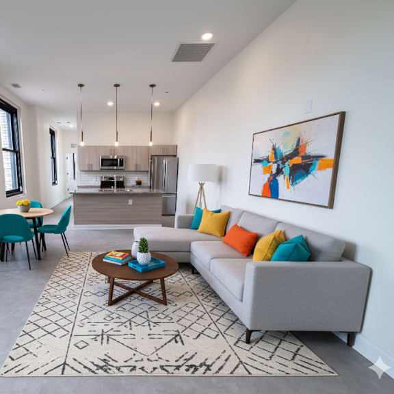 a living room with a grey couch, a coffee table, and a painting on the wall.