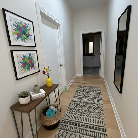 a hallway with a rug, a mirror, and two framed pictures on the wall.
