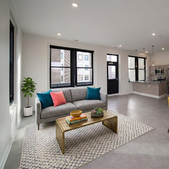 a modern living room with a grey sofa, a coffee table, and a dining table with chairs.