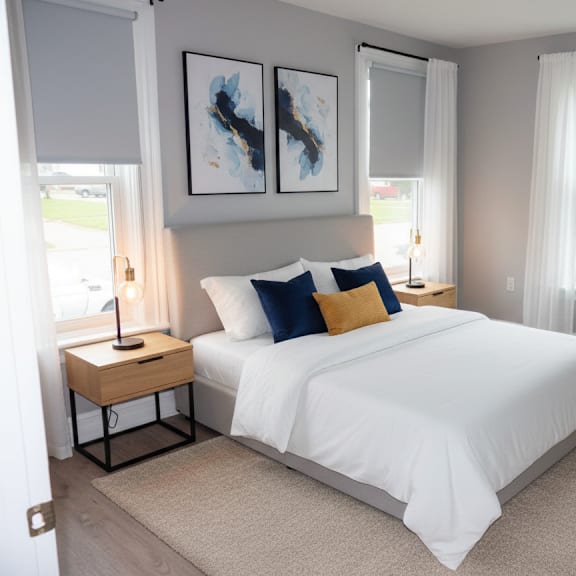 a bedroom with a white bed and a white nightstand with a lamp.