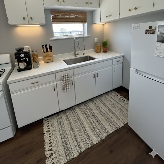 a kitchen with white cabinets and a white fridge.