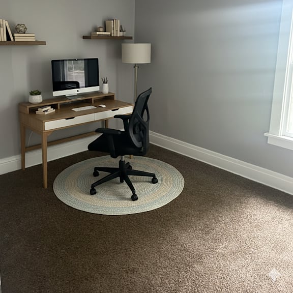 a black chair is in front of a desk with a computer on it.