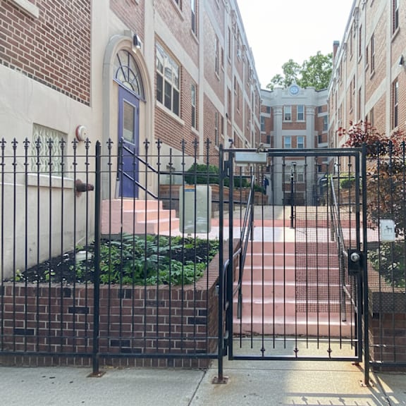 a black iron gate blocks the entrance to a brick building.