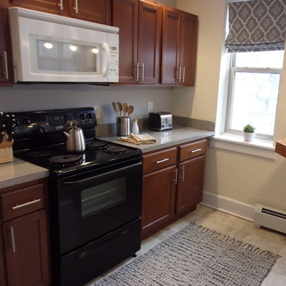 a kitchen with a black stove and wooden cabinets.