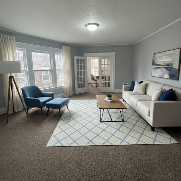 a living room with a blue chair, a white couch, and a coffee table.