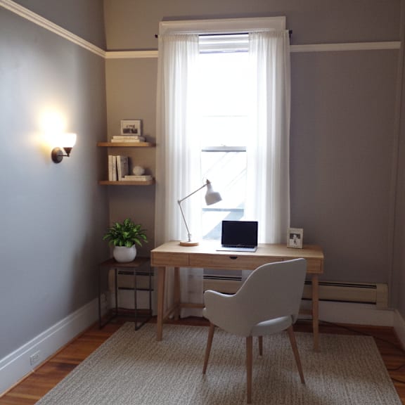 a room with a desk, chair, and a window.