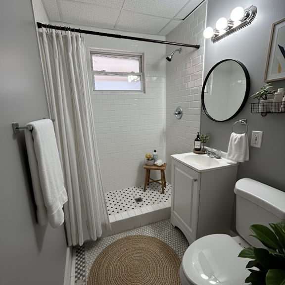 a bathroom with a toilet, sink, and shower.