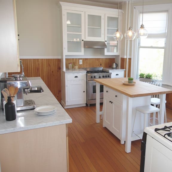 a kitchen with white appliances and wooden floors.