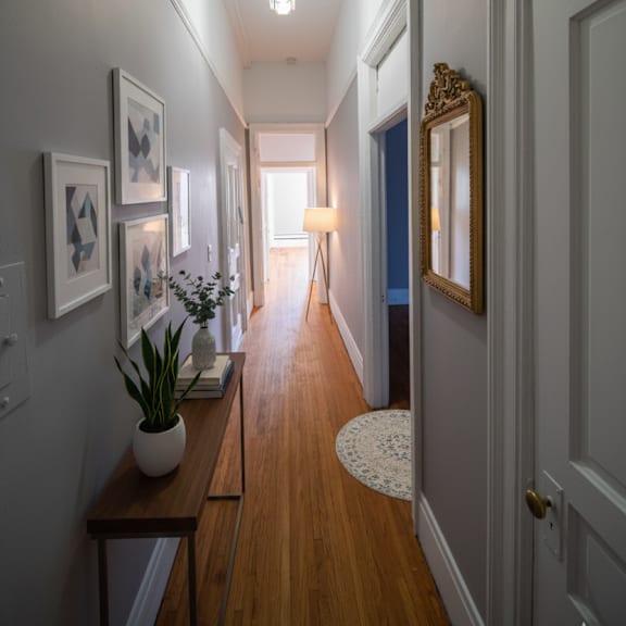 a long hallway with a wooden floor and white walls.