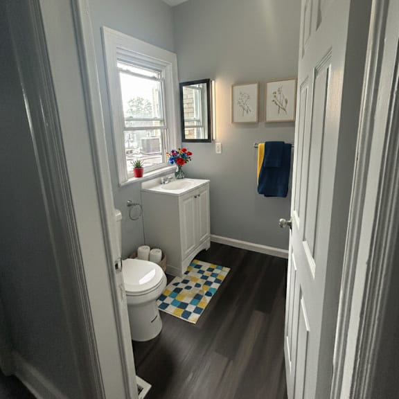 a bathroom with a toilet, sink, and a window.