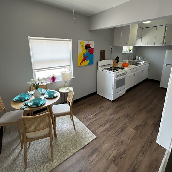 a kitchen with a dining table set for two with a painting hanging on the wall.