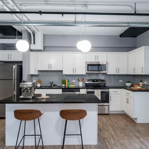 a kitchen with white cabinets and a black countertop.
