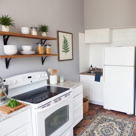 a kitchen with white appliances and a rug on the floor.