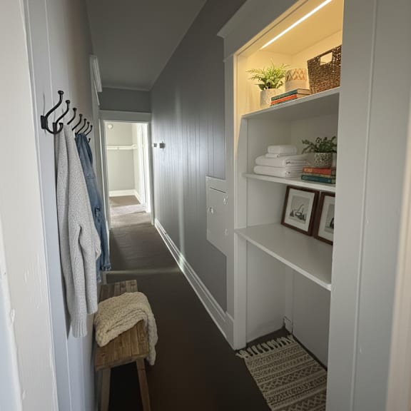 a hallway with a bench and a coat rack.