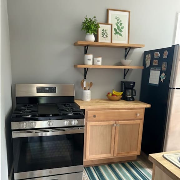 a kitchen with a stove, refrigerator, and wooden shelf.