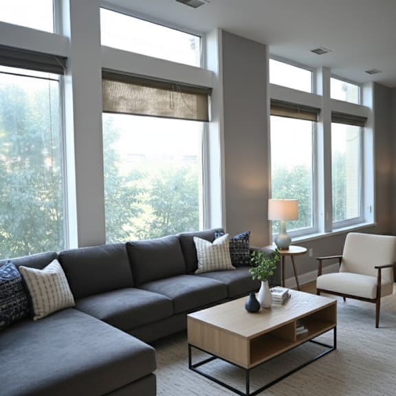 a living room with a grey couch, a wooden coffee table, a chair, and a painting on the wall.