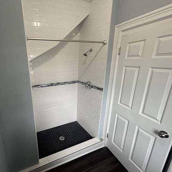 a white door is open to a bathroom with a walk-in shower.