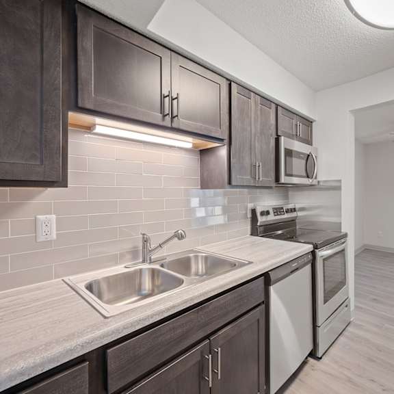 an empty kitchen with stainless steel appliances and wooden cabinets