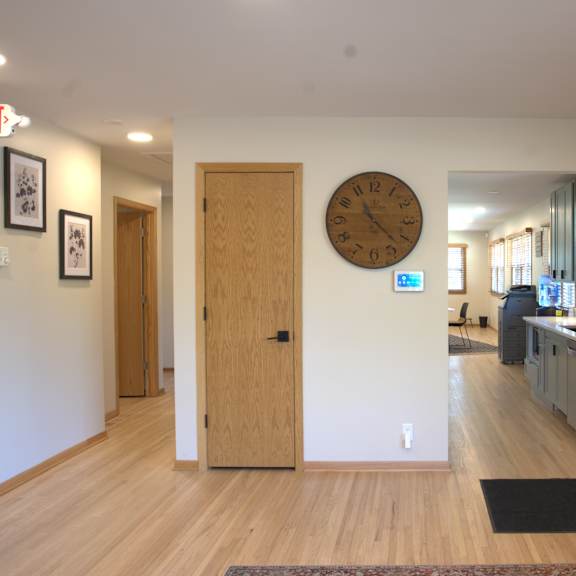 a hallway with a clock on the wall and a couch on the right side.