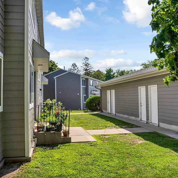 a row of houses with green lawns and trees in the background.