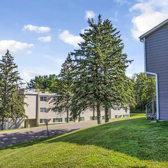 a grassy area in front of a building with trees.
