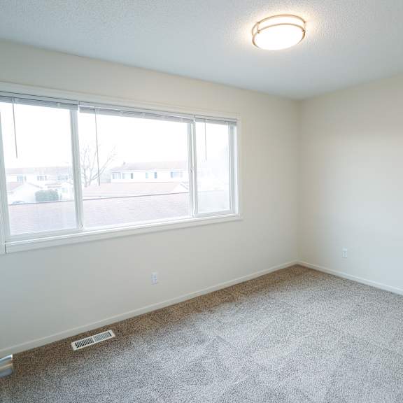 an empty bedroom with a large window and carpeting