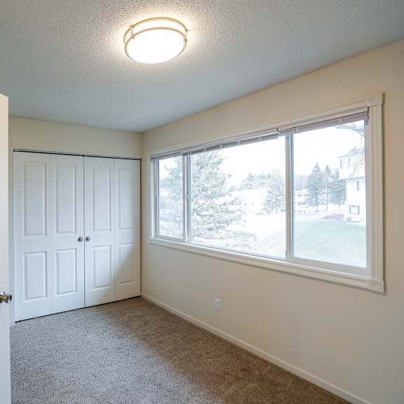 an empty living room with a large window and a white door