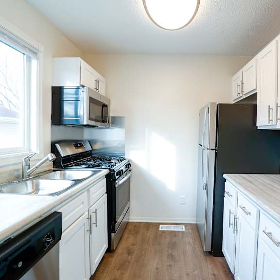 a kitchen with white cabinets and stainless steel appliances and a window