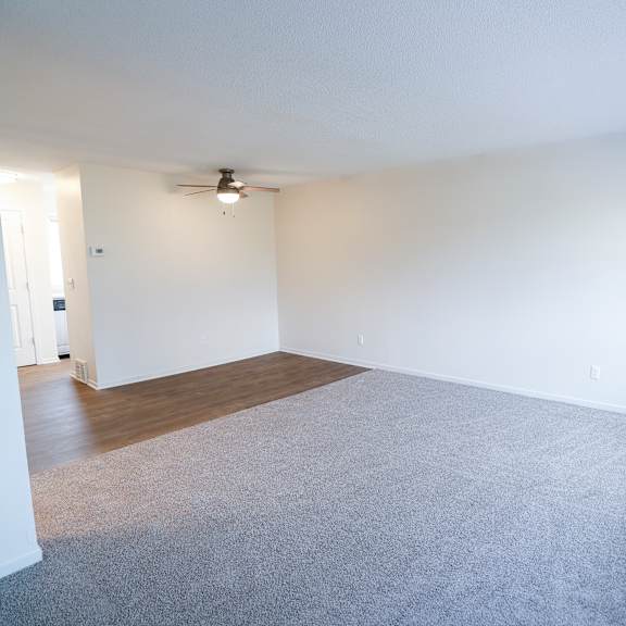 an empty living room with white walls and a ceiling fan