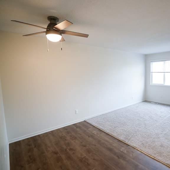 an empty room with a ceiling fan and a window